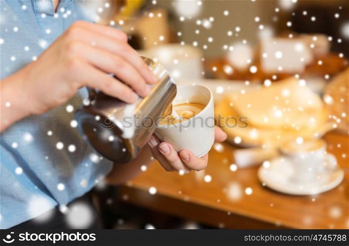 equipment, people and technology concept - close up of woman pouring cream to cup of coffee at cafe bar or restaurant kitchen over snow