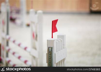 Equitation. Closeup of white obstacle with red flag for jumping horses. Riding competition. Real.