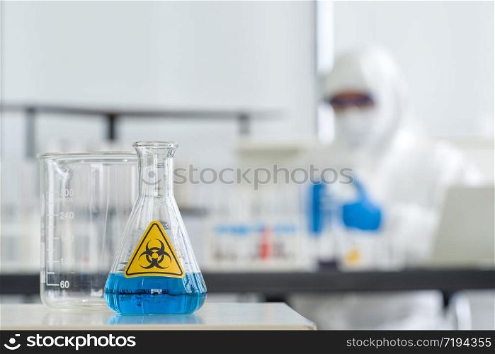 Erlenmeyer Flask contains blue liquid chemicals on a white laboratory table.