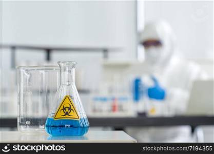 Erlenmeyer Flask contains blue liquid chemicals on a white laboratory table.