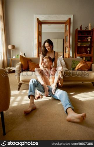 Erotic half dressed couple rest together in home living room. Young attractive girlfriend putting leg on boyfriends shoulder. Dreaming people emotion and romantic relationship. Erotic half dressed couple rest together in home living room