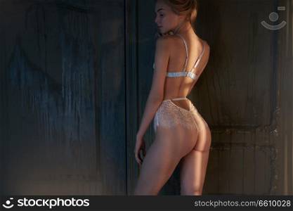 Erotic portrait of young beautiful woman in sexy lingerie. Pretty blonde with sexy figure shows her body in interior. Blue female panties. Lifestyle photo.