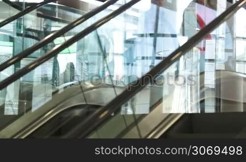 Escalator in shopping centre running up and down with people riding it