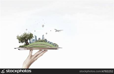 Escape from noisy city. Hand holding metal tray with modern cityscape and calm life concept