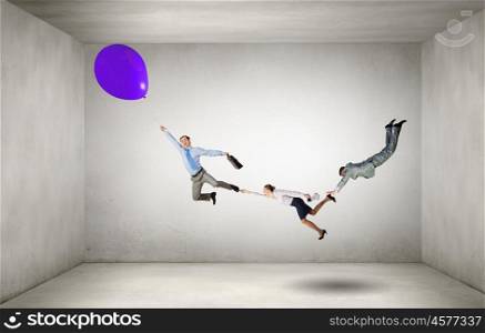 Escape from office. Businesspeople holding each other and flying on colorful balloon