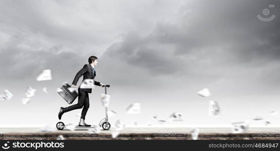 Escape from office. Young cheerful businessman riding scooter against city background