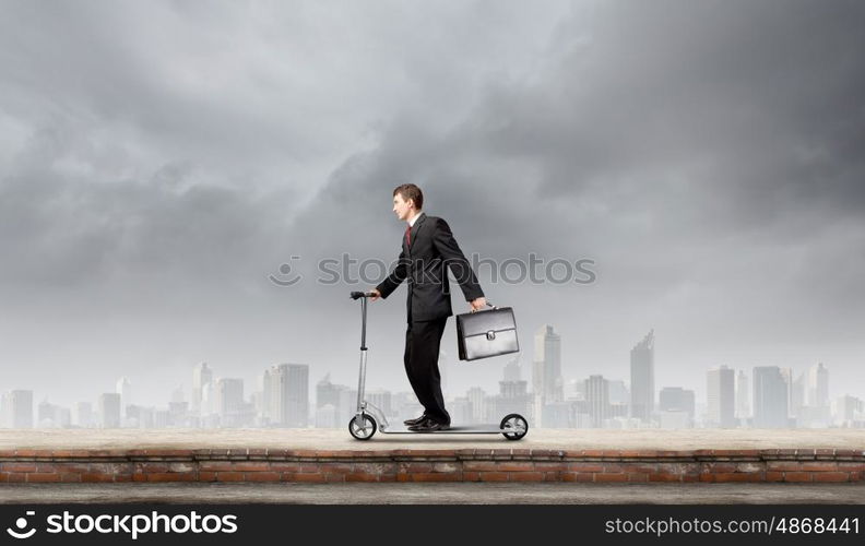 Escape from office. Young cheerful businessman riding scooter against city background