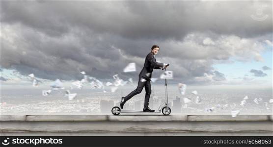 Escape from office. Young cheerful businessman riding scooter against city background