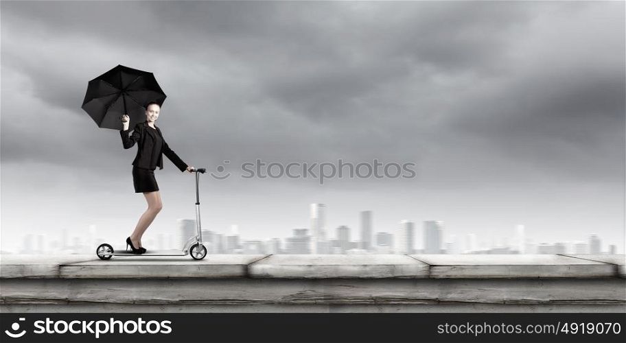 Escape from office. Young cheerful businesswoman riding scooter against city background
