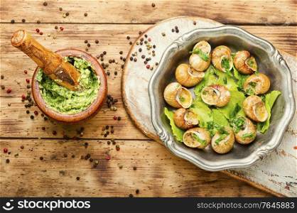 Escargots or snail with garlic butter on rustic wooden background. Bourgogne escargot snails