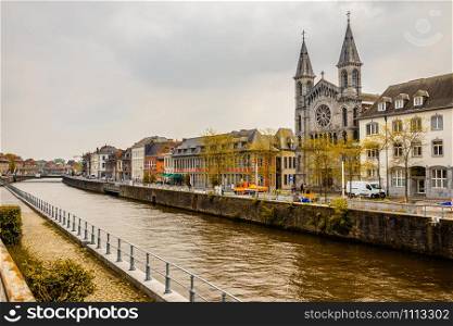Escaut river and street with old belgian houses and facade of church of the Redemptorists of Tournai, Walloon municipality, Belgium