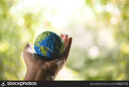 ESG, World Earth Day Concept. Green Energy, Renewable and Sustainable Resources. Environmental and Ecology Care. Hand Holding a Handmade Globe in Nature