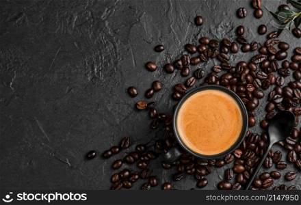 Espresso coffee with fragrant foam in a cup on a black background, flat lay. Breakfast with Italian cafe, top view of a cup of coffee, coffee grains are scattered on the table. copy space for text