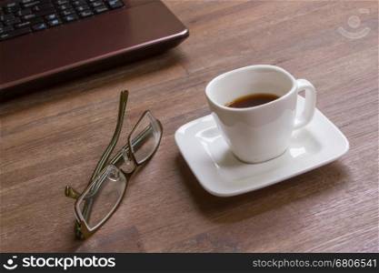 Espresso coffee with glasses on wood floor with laptop