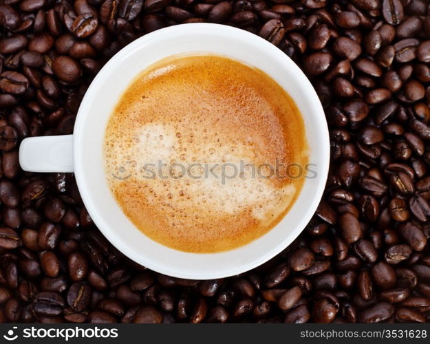 espresso cup in coffee beans, top view