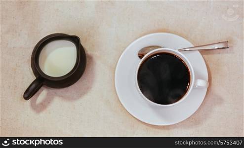 Espresso in white cup and saucer with spoon, milk in jar on grunge vintage background&#xA;