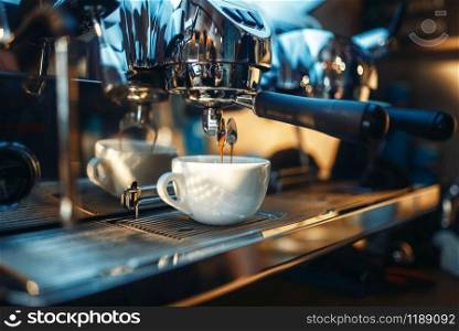 Espresso machine pours fresh black coffee into the cup closeup, nobody. Professional restaurant, cafe or cafeteria business equipment. Espresso machine pours fresh black coffee closeup