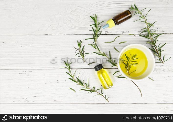 Essential oil bottle natural spa ingredients rosemary oil for aromatherapy and rosemary leaf on wood background / Organic cosmetics with extracts of herbs , top view