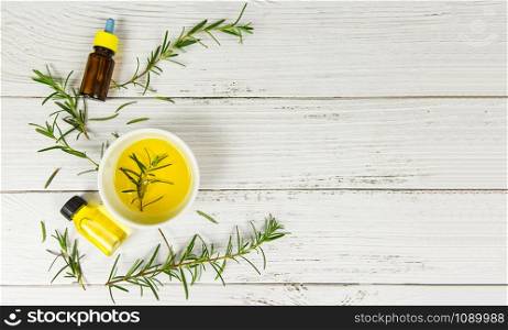 Essential oil bottle natural spa ingredients rosemary oil for aromatherapy and rosemary leaf on wood background / Organic cosmetics with extracts of herbs , top view