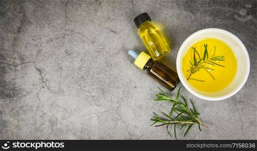 Essential oil bottle natural spa ingredients rosemary oil for aromatherapy and rosemary leaf on gray background / Organic cosmetics with extracts of herbs , top view