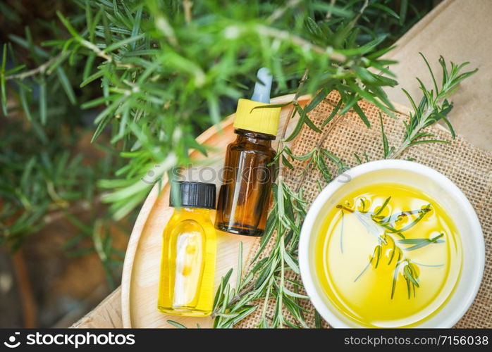 Essential oil bottle natural spa ingredients rosemary oil for aromatherapy and rosemary leaf plant on background / Organic cosmetics with extracts of herbs