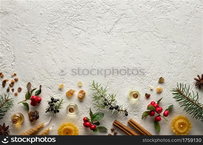 Essential oil bottles with wintergreen, juniper, frankincense and Christmas spices on a white background with copy space