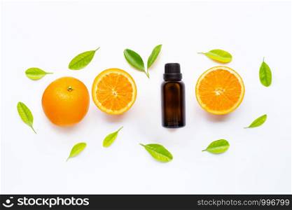 Essential oil with fresh orange fruit and green leaves on white background. Top view