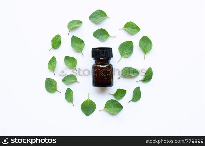 Essential oil with fresh oregano leaves on white background.