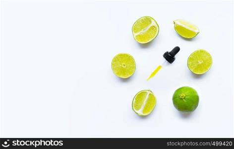 Essential oil with limes on white background.
