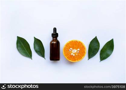 Essential oil with orange and green leaves on white background.