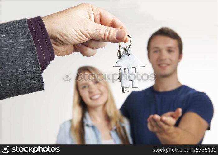Estate Agent Handing Over House Keys To Young Couple