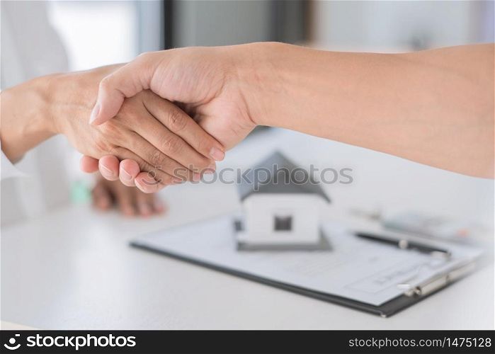 Estate agent in suit sitting in an office desk shaking hands with customer after contract signature accept agreement finish buying or rental real estate for transfer right of property