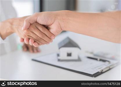 Estate agent in suit sitting in an office desk shaking hands with customer after contract signature accept agreement finish buying or rental real estate for transfer right of property