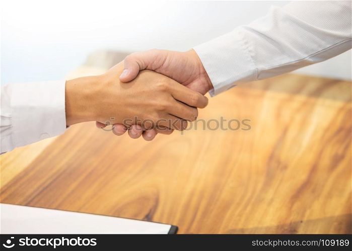 Estate agent shaking hands with customer after contract signature as successful agreement in real estate agency office. Concept of housing purchase and insurance.