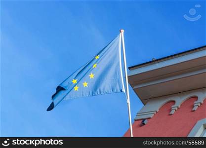 EU flag in front of an old building in the background a blue sky