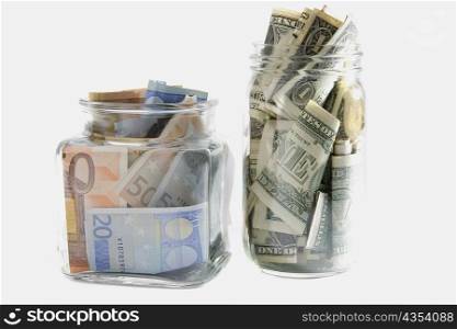 Euro and American bank notes squashed into two jars