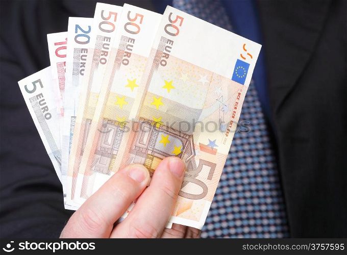 Euro banknotes in male hand on blue background