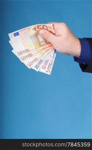 Euro banknotes in male hand on blue background