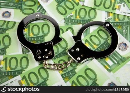 euro banknotes money and handcuffs. crime in the economy