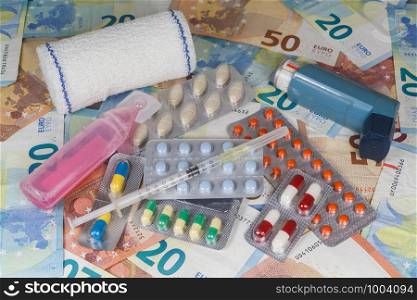 Euro banknotes, pack of pills, inhaler, syringe, bandage and disinfectant as concept for the price of medical treatment