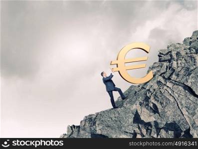 Euro concept. Young businessman rolling up the hill big euro sign