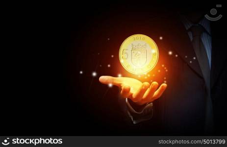 Euro currency. Close up of human hand holding golden euro coin