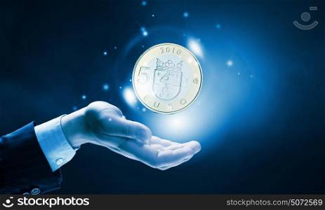 Euro currency. Close up of human hand holding golden euro coin