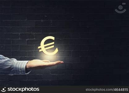 Euro currency. Close up of human hand holding golden euro symbol