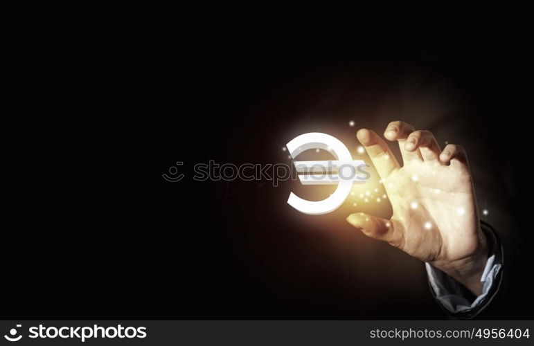 Euro currency. Close up of human hand holding golden euro symbol