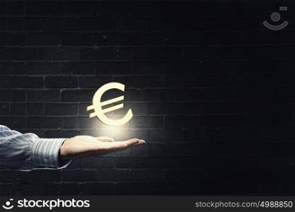 Euro currency. Close up of human hand holding golden euro symbol