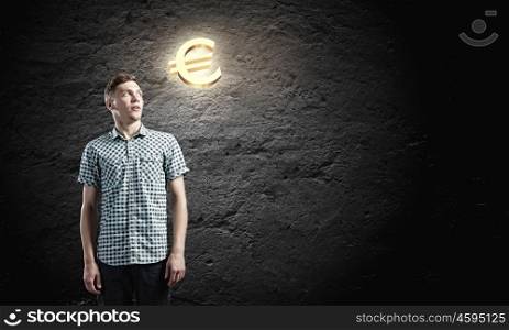 Euro currency concept. Young man and euro sign against dark background