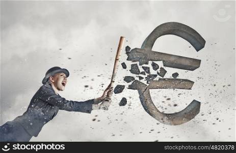 Euro currency fall. Young pretty woman in suit and hat crashing euro sign with baseball bat
