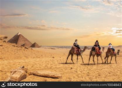 European tourists riding camels near the Pyramids of Egypt.. European tourists riding camels near the Pyramids of Egypt