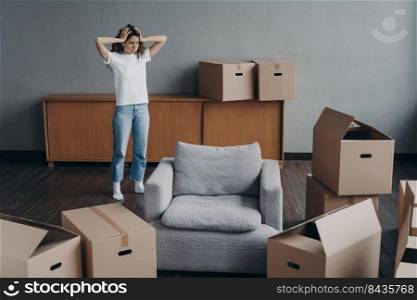 European woman has headache from moving alone. Young lady is exhausted with boxes unloading. Sad attractive girl is going to leave apartment. Annoyed young lady has problem with house.. European woman has headache from moving alone. Young lady is exhausted with boxes unloading.